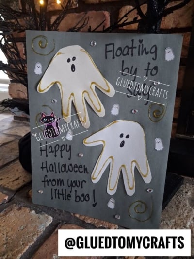 A Halloween card with two ghost shapes made from handprints, gold swirls, small ghost drawings, and the message Floating by to say: Happy Halloween from your little boo!—a perfect addition to your collection of halloween keepsakes.