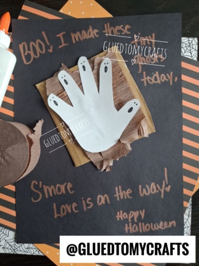 A Halloween craft with a handprint ghost on brown paper and chocolate shapes, orange and black paper, glue, and the message Boo! I made this ghost today. Smore Love is on the way! Happy Halloween—perfect for creating halloween keepsakes that you’ll treasure year after year.