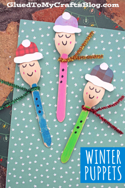 Three wooden spoon winter friends puppets, decorated with cozy hats, pipe cleaner scarves, and button shirts, are arranged on teal starry paper. Perfect as an invitation to play! Text reads WINTER PUPPETS.
