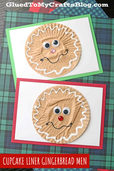Two handmade greeting cards featuring cupcake liner gingerbread men faces with googly eyes, pom-pom noses, and white squiggly mouths, artfully displayed on plaid fabric backgrounds.