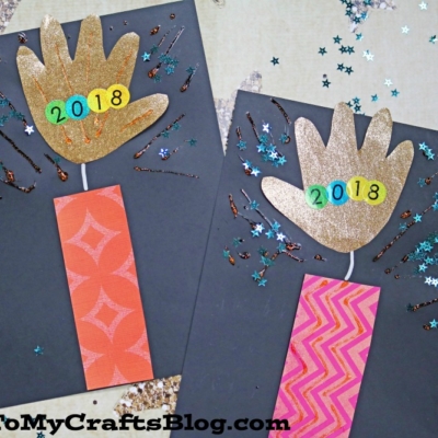 Two dark paper cards display a handprint firework theme with gold handprint cutouts, colorful rectangular bases, glitter, and star-shaped confetti.