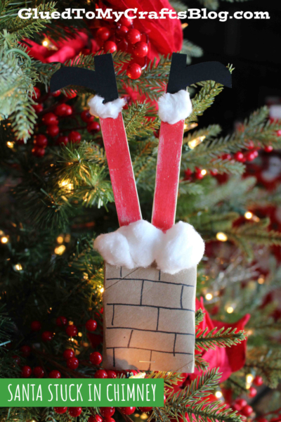 A handmade Christmas ornament resembling Santa’s legs sticking out of a chimney, crafted with red craft sticks, black paper boots, cotton balls, and a brown paper chimney—perfect for fans of classic or toilet roll santa crafts.