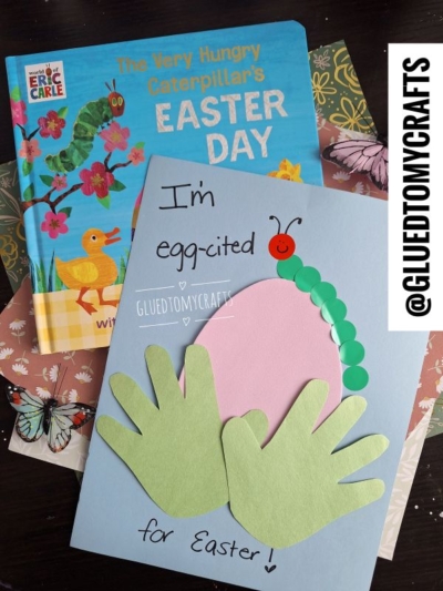 A children's book titled The Very Hungry Caterpillars Easter Day and a handmade Easter card decorated with green handprint cutouts, a caterpillar, foam egg crafts, and the words "I'm egg-cited for Easter!" sit on a table.