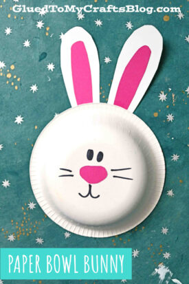 A cute paper bowl bunny craft features a bunny face made from a white paper bowl with paper ears, eyes, nose, mouth, and whiskers, set on a teal background with white star patterns. Text reads PAPER BOWL BUNNY.