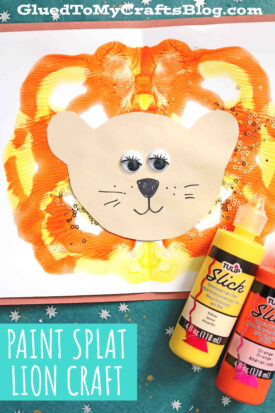 A paint splat lion craft for kids featuring orange and yellow paint splatters as the mane, a beige paper face with googly eyes, a nose, and a smile. Two bottles of paint sit nearby. Text: GluedToMyCraftsBlog.com and Paint Splat Lion Craft.