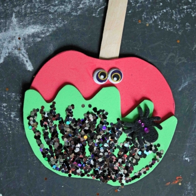 A foam craft shaped like a red apple with green dripping poison, a wooden stick, googly eyes, black glitter, and a spider. Perfect for making caramel apple friends! Text reads POISON APPLE CRAFT and GluedToMyCraftsBlog.com.