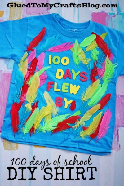 A blue 100 Days of School Flew By T-shirt decorated with colorful feathers and foam letters. This creative DIY project is perfect for celebrating the milestone of 100 days of school.