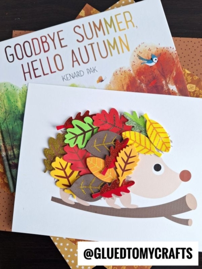 A children’s book titled Goodbye Summer, Hello Autumn sits behind a charming leaf hedgehog craft made of paper leaves, twigs, and a white card, with the handle @GLUEDTOMYCRAFTS at the bottom.