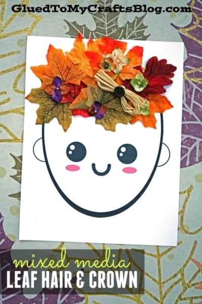 A paper drawing of a smiling face with hair made from colorful artificial leaves and small flowers, beautifully showcasing mixed media leaf hair, labeled LEAF HAIR & CROWN at the bottom.