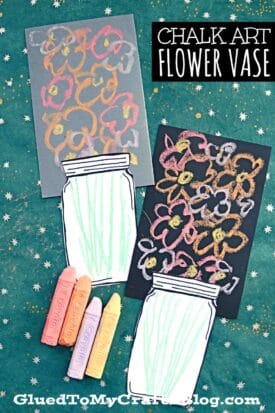 Three chalk art flowers in paper vases are displayed on a teal, starry background. Four pastel chalks lie beside the artwork. Text reads “Chalk Art Flower Vase”.