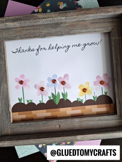 A framed handmade card with flower art and the words Thanks for helping me grow! on white paper—perfect for celebrating National Grandparent’s Day. Decorative paper with flower patterns peeks from behind. The @GLUEDTOMYCRAFTS handle is at the bottom.