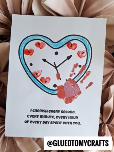 A heart-shaped clock drawing with red fingerprints as numbers, a handprint with a glittery heart, and the text, I cherish every second, every minute, every hour of every day spent with you—perfect for celebrating National Grandparent’s Day.