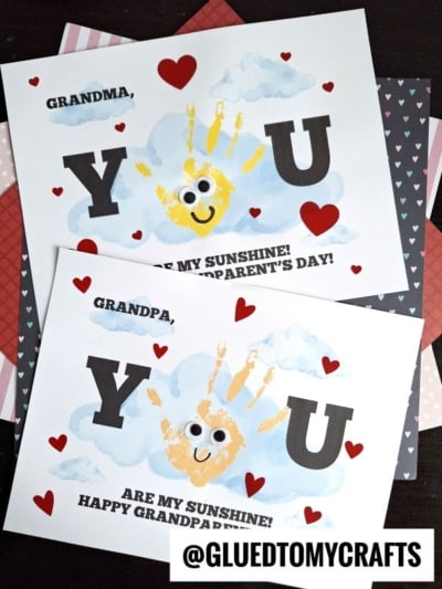 Two Grandparents Day cards with handprint suns, clouds, large YOU, red hearts, and the message: Grandma/Grandpa, you are my sunshine! Happy Grandparents Day! on a patterned background—perfect for celebrating National Grandparent’s Day with love and creativity.