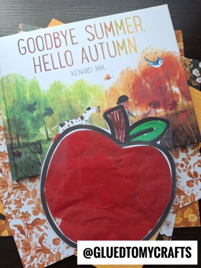 A children’s book titled Goodbye Summer, Hello Autumn by Kenard Pak is displayed with patterned paper and a large stained glass apple craft in the foreground. A watermark reads @GLUEDTOMYCRAFTS.