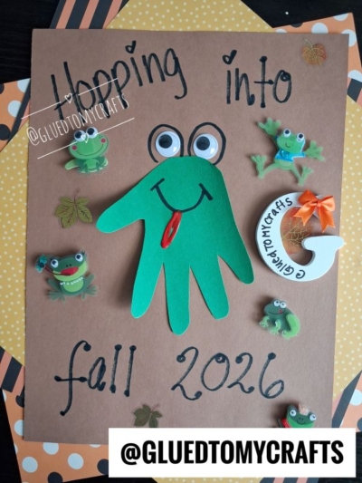 A brown paper with Hopping into fall 2026 features a green handprint frog with googly eyes, surrounded by frog stickers, leaves, and polka dot borders—perfect for those searching for creative fall keepsake ideas. @GLUEDTOMYCRAFTS is displayed at the bottom.