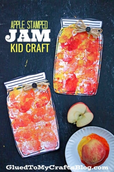Two paper jars decorated with red and yellow apple-stamped paint sit on a dark surface. Below them are a halved apple, a whole apple, and a small white plate. Text reads: Apple Stamped Mason Jar Jam Kid Craft.
