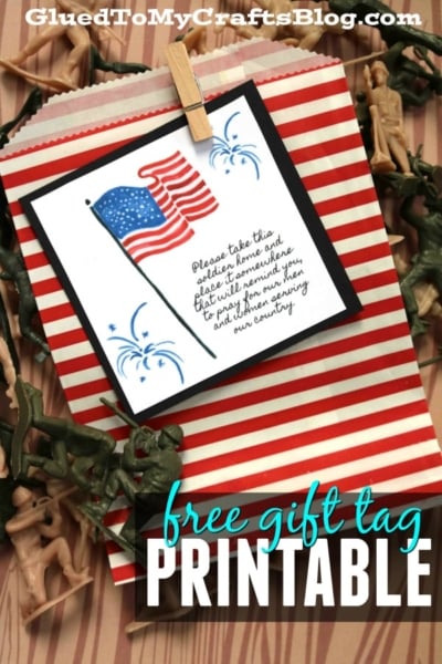 A red and white striped gift bag with plastic toy soldiers, featuring a card with an American flag, blue fireworks, and a patriotic message. The image reads “free gift tag PRINTABLE—take this soldier as a token of thanks.”.