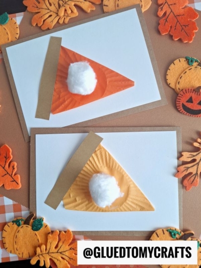 Two handmade greeting cards feature cupcake liner pumpkin pie slices made from orange and tan paper with a cotton ball as whipped cream. They are surrounded by felt pumpkin and leaf decorations on a brown background. @GLUEDTOMYCRAFTS is printed at the bottom.