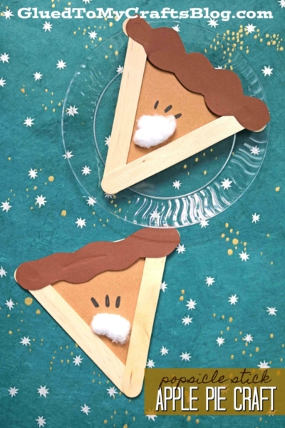 Two handmade craft stick apple pies, created from popsicle sticks, brown paper, and cotton balls, are displayed on a teal star-patterned background. Popsicle stick apple pie craft is written at the bottom.