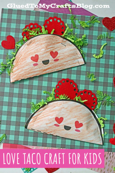 Two paper love tacos with heart-shaped eyes and smiles are decorated with green paper lettuce and red hearts, displayed on a green and brown plaid background. Text reads, LOVE TACO CRAFT FOR KIDS.