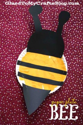 A fun paper plate bee craft for kids made with yellow and black tissue paper, wings, and antennae on a red polka dot background. Text reads paper plate BEE and “GluedToMyCraftsBlog.com”.