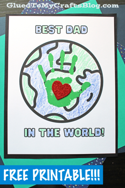 A handmade "best dad in the world card" features a child’s green handprint with a red glitter heart over Earth. Text reads Who's the Best Dad in the World! and “Free Printable!!!” at the bottom.