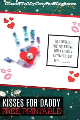 A handmade Fathers Day card features a child’s colorful handprint, a red paper heart topped with foil candy, and the message, “I’m blowing kisses for daddy your way, with a wish for a Happy Father’s Day!” Decorated with hearts and kiss marks.