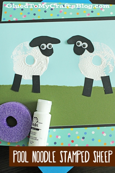This fun pool noodle craft for kids features two sheep made by stamping white paint with a pool noodle, with black paper legs, heads, and googly eyes on blue and green paper, all surrounded by a colorful border and craft supplies.