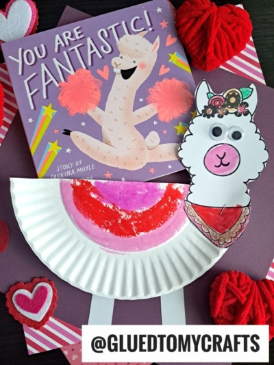 Children’s book “You Are Fantastic!” with an illustrated llama cover, beside two adorable crafts: a decorated paper plate llama and a playful paper llama face. Red and pink heart decorations surround these cheerful creations.