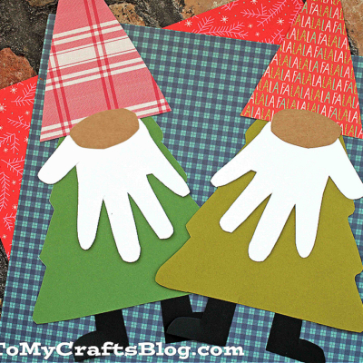 Two tree gnome crafts made from colorful patterned paper, with handprint beards and plaid hats, are displayed on red and blue plaid sheets.