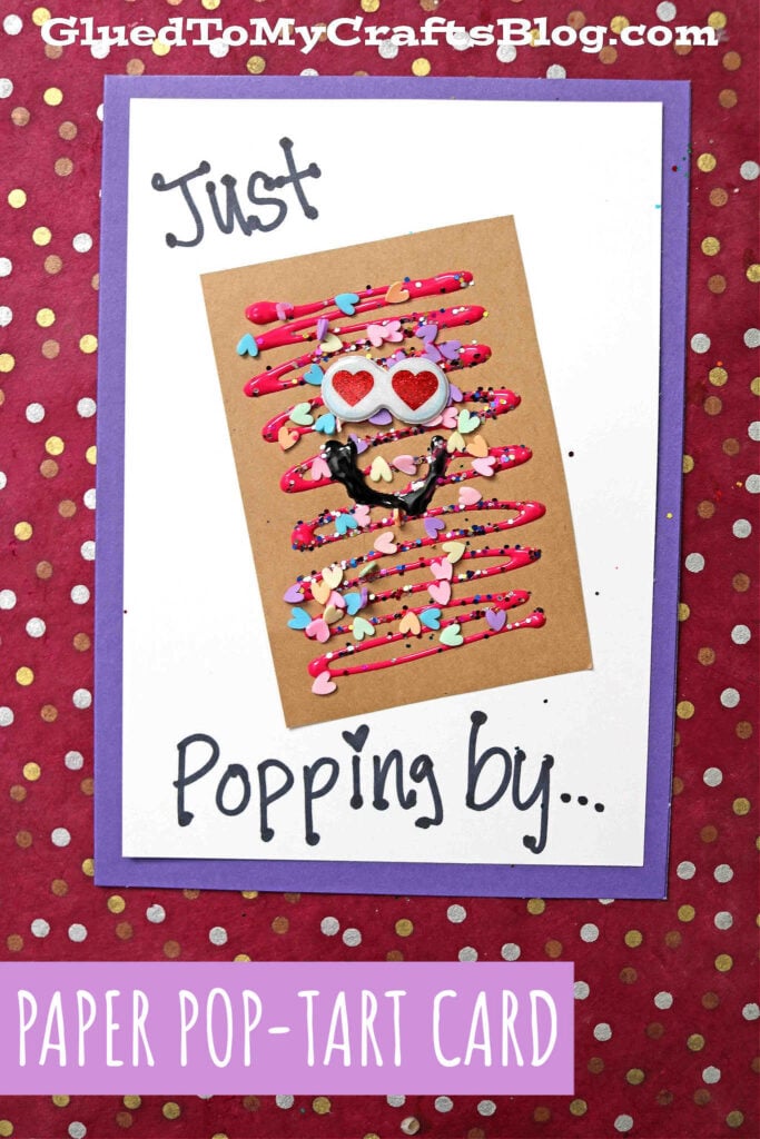 A handmade paper Pop-Tart card with heart sprinkles, googly eyes, and a smile. “Just Popping by…” appears on the front. The card features a purple background with white dots and a banner reading PAPER POP-TART CARD.
