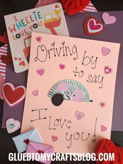 A handmade Valentine’s card features a hedgehog made from a cupcake liner, heart decorations, and the sweet phrase “Driving by to say I love you!”—perfect for a camper or kids who adore creative card-making.
