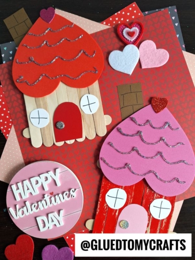 Valentine’s Day crafts featuring pink and red paper gingerbread house cutouts, decorated with hearts and glitter, set on patterned backgrounds. A sign reads “HAPPY Valentine’s DAY” with @GLUEDTOMYCRAFTS at the bottom.