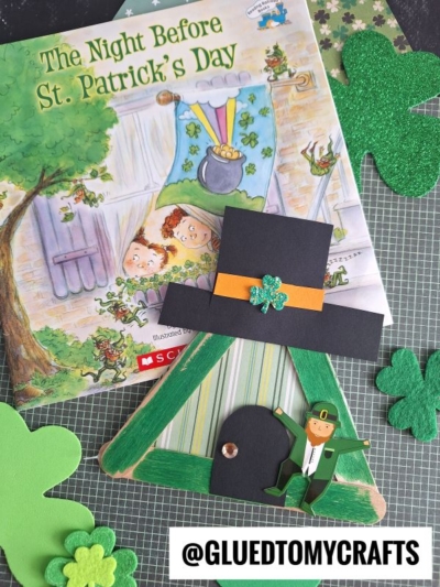 A children’s book titled “The Night Before St. Patrick’s Day” is shown with St. Patrick’s Day crafts, including a popsicle stick leprechaun house, a leprechaun hat, and shamrock decorations, all set on a playful patterned background.
