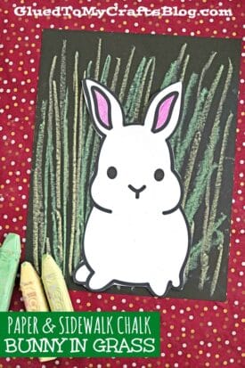 A white paper bunny with pink ears sits over green chalk-drawn grass on black paper, perfect for bunny art with chalk pastels. Three pastel chalk pieces rest nearby, all on a red polka dot background. Blog info appears in the top and bottom text.