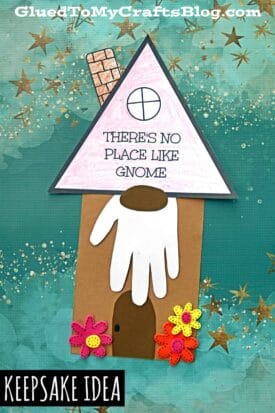 A charming gnome house craft made from paper, featuring a handprint beard, colorful flowers, and the phrase “there’s no place like gnome for the holidays” on the roof. The teal background sparkles with gold stars.