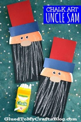 Two paper chalk art Uncle Sam crafts with red and blue hats, textured beards in white chalk on black paper, and peach faces with googly eyes are displayed on a starry background next to a box of Crayola chalk.