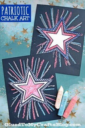 Two pieces of patriotic chalk art featuring white stars outlined in red and blue, with chalk rays radiating from each star on black paper. Pieces of red, blue, and white chalk add to the festive, patriotic chalk art display.