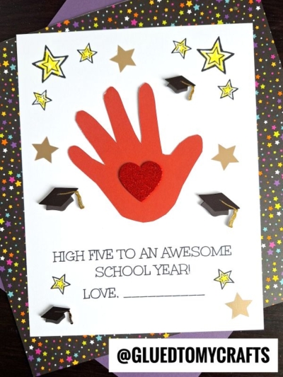 A card with a red high five handprint, a red glitter heart in the center, surrounded by star and graduation cap stickers. Text reads HIGH FIVE TO AN AWESOME SCHOOL YEAR! LOVE, ________. @GLUEDTOMYCRAFTS at the bottom.