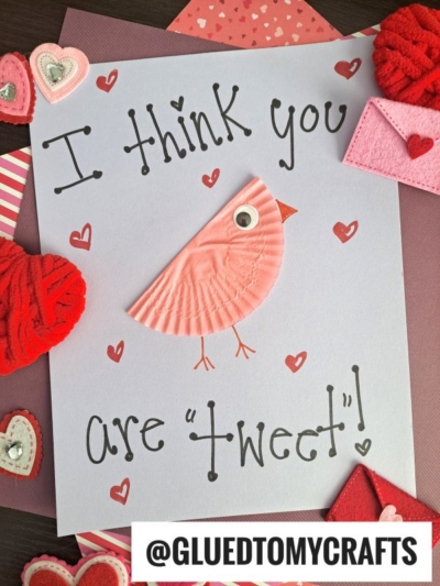A handmade love bird valentine card features a pink cupcake liner bird with a googly eye. The card reads “I think you are ‘tweet’!” and is surrounded by heart decorations. @GLUEDTOMYCRAFTS appears at the bottom.