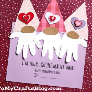 Valentine gnome craft with handprint beards, heart accents, and pink hats are glued to a purple card that says, "I love you gnome matter what! Happy Valentine’s Day! Love ________" on a red dotted background.
