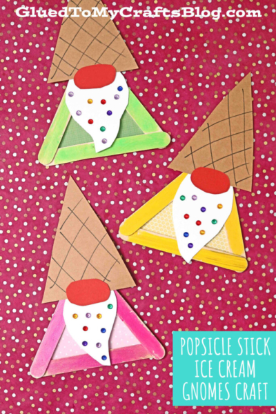 Three colorful popsicle stick ice cream gnome crafts shaped like gnomes with waffle cone hats, white beards, and red noses are arranged on a red background with white dots.