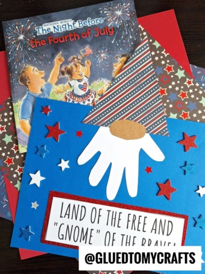 A children’s book titled The Night Before the Fourth of July lies on red and blue paper. Below is a handprint patriotic gnome craft, featuring stars and a sign that says Land of the Free and Gnome of the Brave.