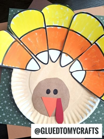 A paper plate candy corn turkey craft featuring a tail made of candy corn-shaped cutouts.