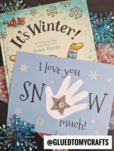 A children’s book titled Its Winter! sits behind a winter-themed craft featuring a handprint, snowflakes, and the cute message I love you snow much! @GLUEDTOMYCRAFTS is written at the bottom.