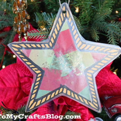 A stained glass Christmas star shaped object adorned with shimmering gold glitter.