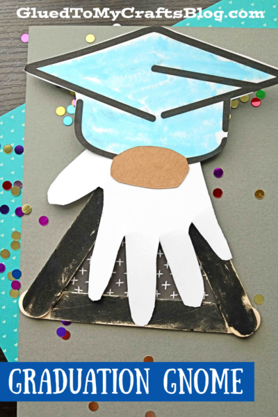A handmade popsicle stick graduation gnome craft features a blue cap and white beard on a gray background, surrounded by colorful confetti. The text GRADUATION GNOME appears at the bottom.