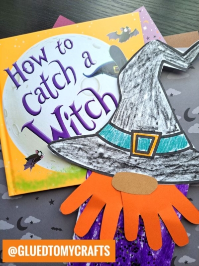 A children’s book titled How to Catch a Witch lies on a table, surrounded by a handmade paper bag witch hat, hand-shaped orange cutout, and bat decorations. The image is tagged @GLUEDTOMYCRAFTS.