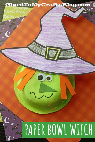 A paper bowl witch made from a green painted paper bowl, orange paper strips for hair, a purple witch hat, and a drawn face is displayed on festive Halloween-themed paper. Text reads Paper Bowl Witch.