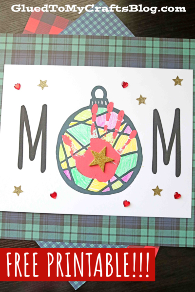 Handmade MOM card featuring a colorful mom Christmas ornament and a pink handprint in the center, decorated with gold stars and red hearts on white paper. The green plaid background adds festive charm. Text reads FREE PRINTABLE!!! and website name.